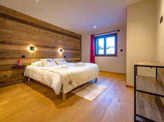 Experience cozy mountain living in this charming bedroom featuring a rustic wooden accent wall and a comfortable queen-sized bed.