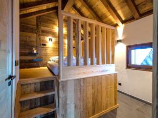 Discover this charming rustic bedroom featuring a cozy loft bed accessed by wooden stairs.