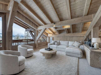 Experience luxury mountain living in this stunning chalet living room, featuring exposed wooden beams and a vaulted ceiling that create a warm, rustic ambiance.