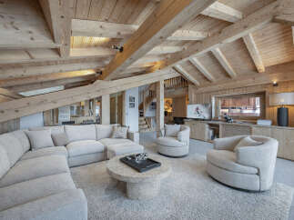 Experience luxury mountain living in this stunning chalet, featuring a spacious sectional sofa and plush armchairs perfect for cozy evenings.