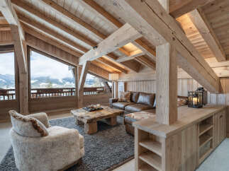 Experience luxurious mountain living in this stunning chalet living room, featuring a cozy leather sectional and a unique live-edge coffee table.