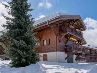 Experience the charm of a winter wonderland with this stunning wooden chalet nestled in a snowy landscape.