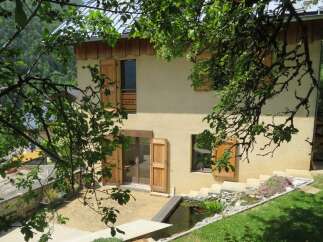 Discover this charming property nestled in a serene mountain setting, featuring a traditional house with wooden shutters and a light-colored stucco exterior.