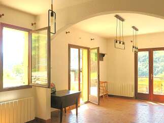 This spacious room features large windows and glass doors that flood the space with natural light, offering picturesque views of the surrounding greenery.