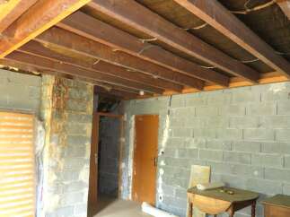 This unfinished interior space features exposed wooden beams and concrete block walls, offering a blank canvas for renovation.