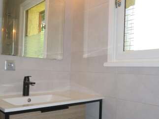 This modern bathroom features a sleek vanity with a contemporary black faucet and a clean white sink.