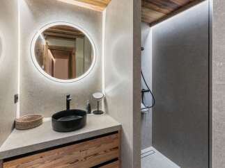Experience modern luxury in this bathroom featuring a sleek black vessel sink atop a natural wood vanity.