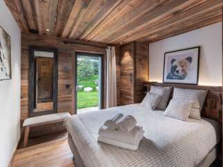 Experience rustic charm in this cozy bedroom featuring warm wood paneling throughout and a comfortable king-sized bed.