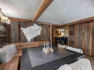 Experience rustic charm in this dining area, featuring a large wooden bench adorned with plush white cushions.