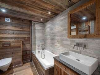 Experience rustic luxury in this stunning bathroom, featuring a deep soaking tub and a sleek modern sink.