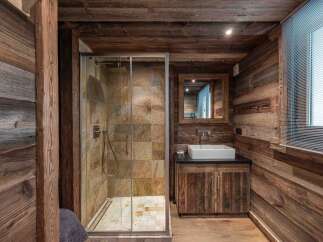 Experience rustic luxury in this charming bathroom, featuring a spacious walk-in shower with natural stone tile accents.