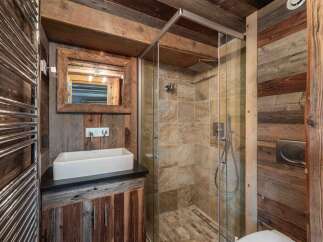 Experience rustic charm in this unique bathroom featuring a spacious walk-in shower with stone tile accents and a modern vessel sink atop a reclaimed wood vanity.