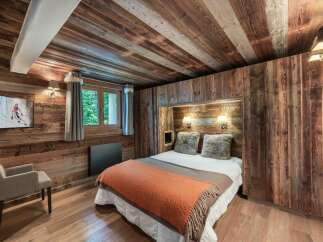 Experience rustic charm in this cozy bedroom, featuring warm wood paneling on the walls and ceiling.