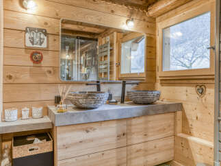 Experience rustic luxury in this charming bathroom, featuring a double vanity with stone vessel sinks and modern black faucets.