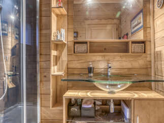 Experience rustic charm in this bathroom featuring a modern glass vessel sink and a sleek chrome faucet, all set against warm, natural wood paneling.