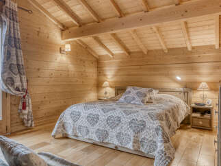 Experience rustic charm in this cozy wooden bedroom, featuring a comfortable queen-size bed adorned with a heart-patterned quilt.