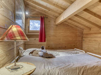 Experience cozy living in this charming wooden cabin bedroom, featuring a comfortable bed adorned with plush stuffed animals.