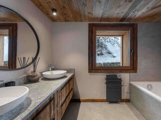 Experience rustic luxury in this mountain bathroom, featuring a double vanity with stone countertops and wooden cabinetry.