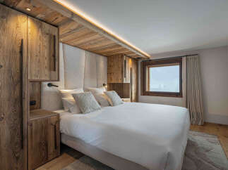 Experience rustic luxury in this charming bedroom, featuring warm, natural wood accents and a plush, upholstered headboard.