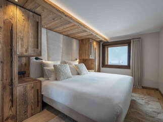 Experience ultimate comfort in this luxurious bedroom, featuring a plush king-size bed adorned with soft pillows and a textured throw.