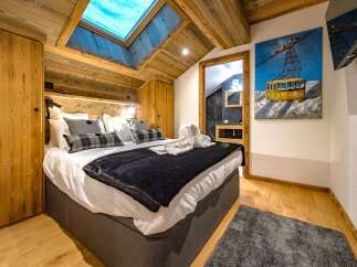 Experience ultimate comfort in this charming bedroom, featuring a luxurious king-size bed adorned with plush pillows and a cozy dark blanket.