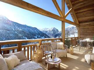 Experience breathtaking mountain views from this luxurious chalet balcony, perfect for enjoying a serene winter escape.