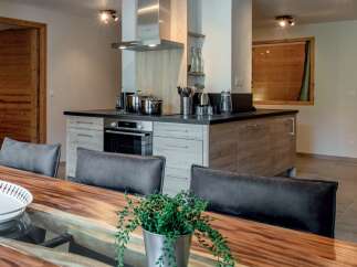 Experience modern living in this stunning kitchen and dining area, featuring sleek cabinetry and a spacious wooden dining table perfect for gatherings.