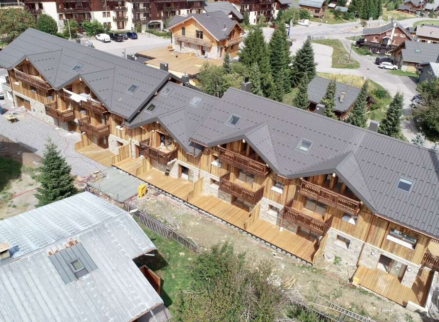 Experience luxury mountain living in this stunning chalet-style property, featuring a modern dark metal roof and warm wooden exterior.