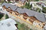 Experience luxury mountain living in this stunning chalet-style property, featuring a modern dark metal roof and warm wooden exterior.