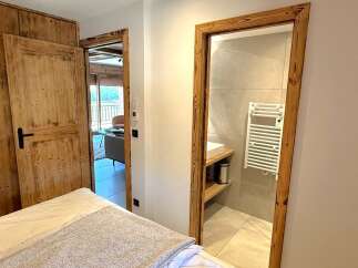 Experience rustic charm and modern comfort in this inviting bedroom, featuring a cozy bed and direct access to a stylish bathroom.