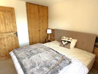 Experience rustic charm in this cozy bedroom, featuring a plush bed adorned with a decorative throw and pillows.