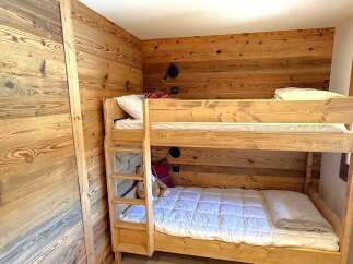 Experience cozy living in this charming room featuring a sturdy wooden bunk bed, perfect for families or guests.