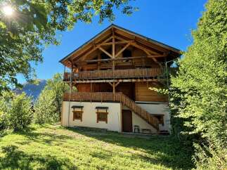 Experience the charm of this rustic wooden chalet nestled amidst lush greenery and bathed in sunlight.
