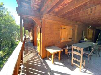 Experience rustic charm with this wooden cabin featuring a spacious covered porch perfect for enjoying the surrounding nature.