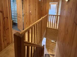 Experience rustic charm in this wood-paneled home, featuring a beautiful staircase with wooden railings.