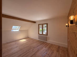 Experience rustic charm in this attic bedroom, featuring a beautiful wooden floor and exposed beam.