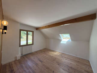 Discover this charming attic room featuring a beautiful wooden floor and exposed beams, creating a warm and rustic ambiance.