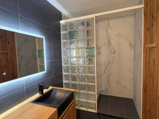 Experience modern luxury in this stunning bathroom featuring a sleek vanity with a unique black sink and a built-in illuminated mirror.