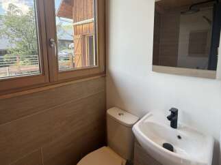 This modern bathroom features a sleek white sink with a black faucet, complemented by a matching toilet.