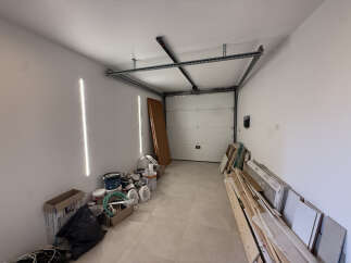Discover this spacious garage, perfect for storage or a workshop, featuring a modern sectional garage door and ample wall space for shelving.