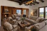 Experience rustic luxury in this stunning mountain lodge living room, featuring a grand stone fireplace and exposed wooden beams.