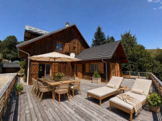 Enjoy al fresco dining on this expansive wooden deck, complete with a large outdoor dining table and chairs under a shaded umbrella.