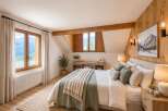 Experience rustic charm in this mountain-view bedroom, featuring a cozy bed adorned with plush pillows and warm throws.