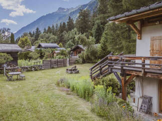 Experience the charm of mountain living in this picturesque property, featuring a cozy wooden cabin nestled amidst lush greenery and towering trees.