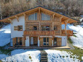 Experience the charm of this stunning wooden chalet nestled in a snowy mountain landscape.