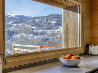 Experience breathtaking mountain views from this stunning property, featuring a spacious kitchen with a large window overlooking a snow-covered landscape.