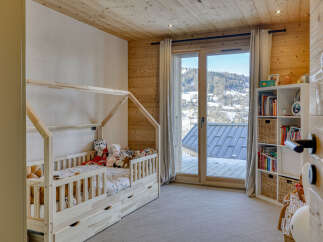 This charming children's bedroom features a cozy wooden house-shaped bed with plush toys, perfect for a peaceful night's sleep.
