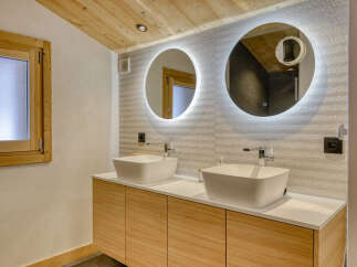 Experience modern luxury in this stunning bathroom featuring dual vessel sinks atop a sleek wooden vanity.