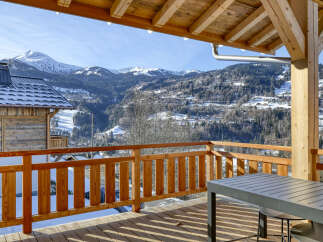 Experience breathtaking mountain views from this stunning chalet, featuring a spacious wooden deck perfect for enjoying the alpine scenery.