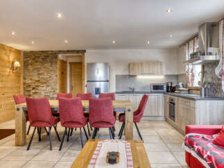 This charming dining area and kitchen features a rustic wooden dining table with six plush red chairs, perfect for family meals.